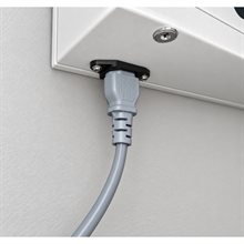 Grå strömkabel ansluten till vit enhet med svart kontakt och ett nyckelhål ovanför.